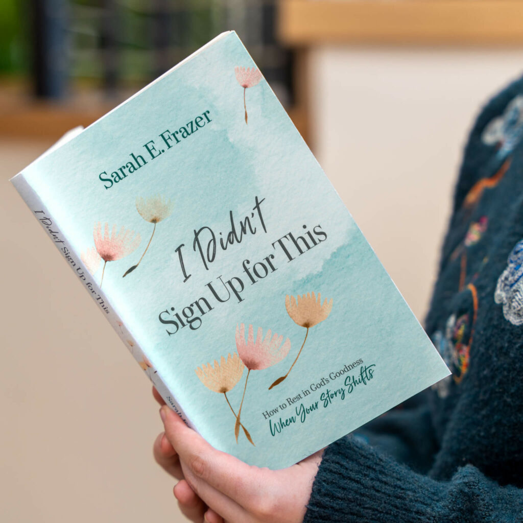 A woman reading the book 'I Didn't Sign Up for This' by Sarah Frazer, contemplating life's challenges and finding faith amidst adversity.