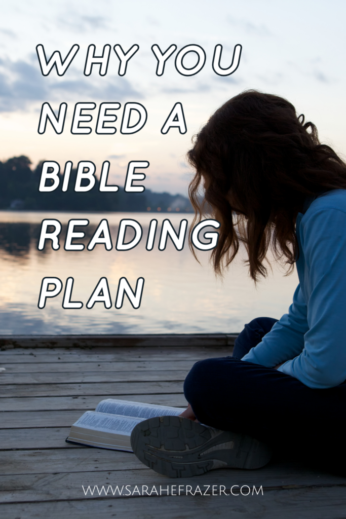 Woman with medium length brown hair sits on a dock overlooking a lake at dusk reading her open Bible. Text overlay reads "why you need a Bible reading plan"