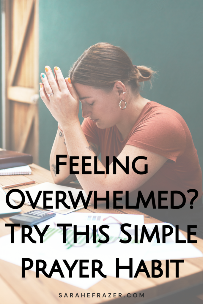 woman prays at her desk with papers around her. Text overlay reads: feeling overwhelmed? try this simple prayer habit