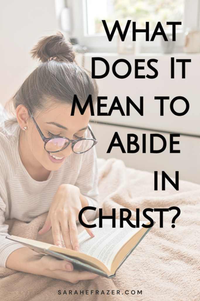 Woman reads her Bible lying on a bed. Text reads: What does it mean to abide in Christ Jesus