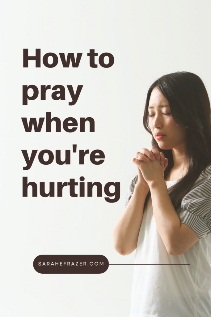 Asian woman stands with folded hands. Text reads: How to pray when you're hurting